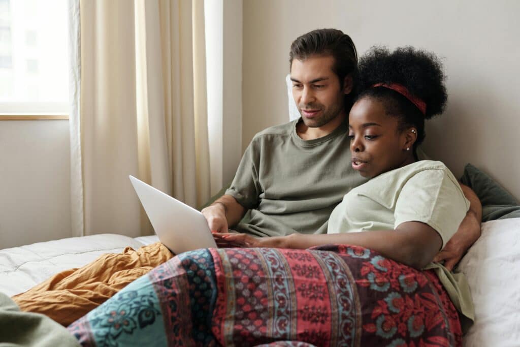 couple in bed looking laptop