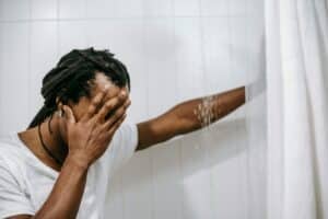 man sitting in shower with water on