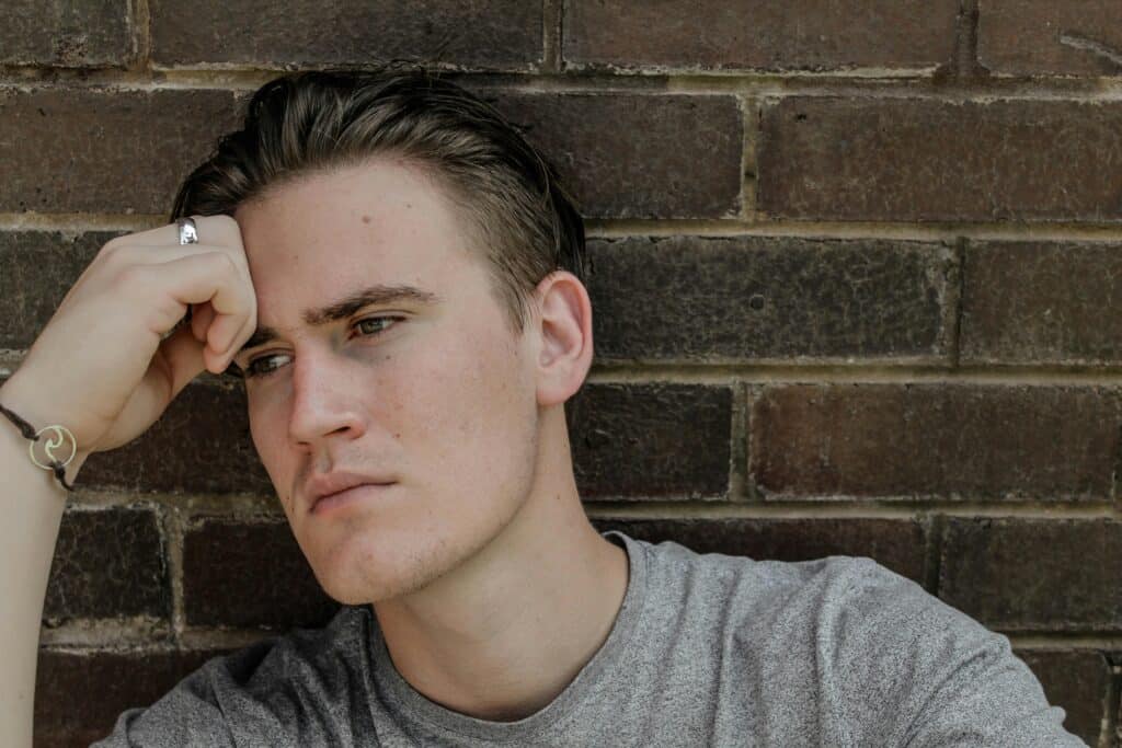 man sitting against wall thinking