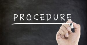 A hand holding a chalk and drawing a white underline under the word PROCEDURE on a dark chalkboard, symbolizing a procedure or process.