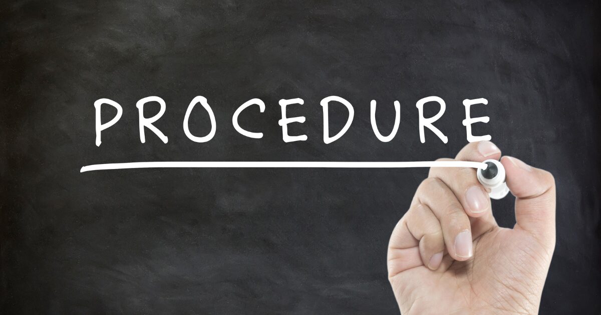 A hand holding a chalk and drawing a white underline under the word PROCEDURE on a dark chalkboard, symbolizing a procedure or process.
