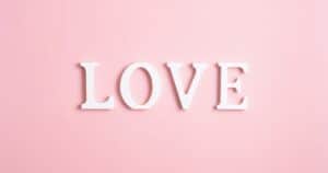 White letters spelling LOVE on a soft pink background, like word art for romance