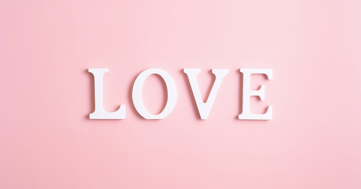 White letters spelling LOVE on a soft pink background, like word art for romance