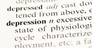Close-up of a printed dictionary page focusing on the word 'depressed' and surrounding definitions.