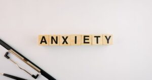 - Treat Mental Health Tennessee Wooden blocks spell ANXIETY on a pale desk, with a pen and ruler nearby.