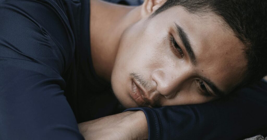 Man resting his head on folded arms, looking tired or sad in a close-up portrait